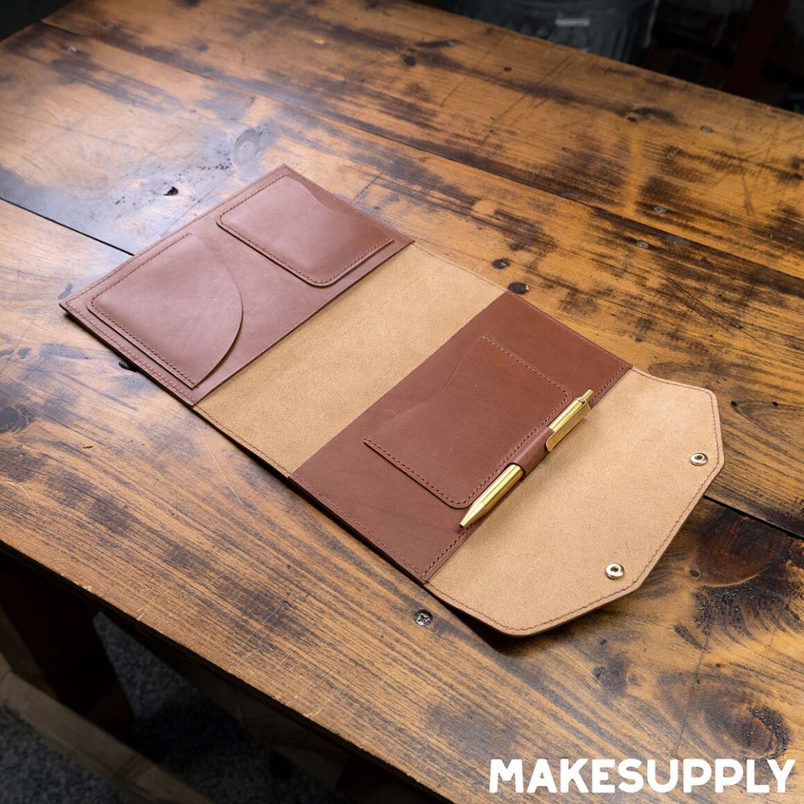 Open A5 leather notebook cover showing interior pocket and pen holder made from PDF pattern