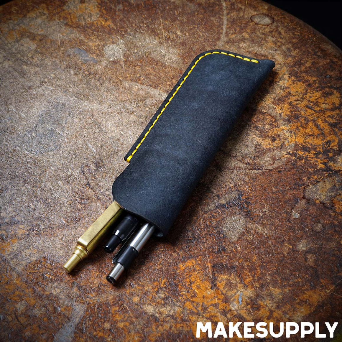 Leather pen sleeve holding pens with visible hand stitching