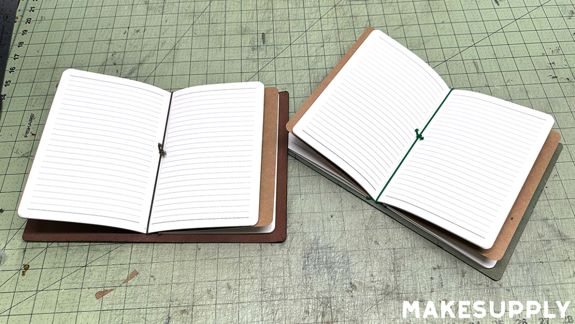 A5 bifold leather notebook covers opened flat showing notebook inserts held in place with elastic cord